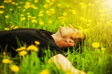 Foto op Canvas man liggend op gras op zonnige dag © katalinks