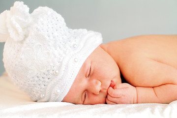 sleeping newborn baby girl in white hat