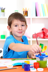 Cute little boy painting in his album