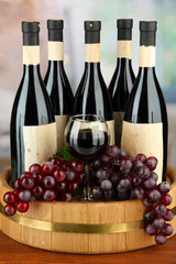 Composition of wine bottles, glass and  grape,on wooden barrel,