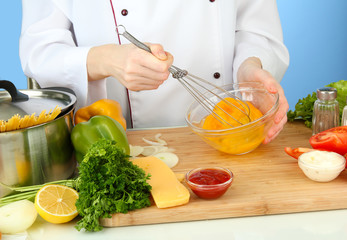 Female hands blending eggs in glass bowl