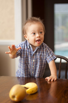 Down Syndrome child reaching for fruit on table