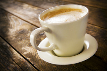 A cup of coffee on the wooden board.