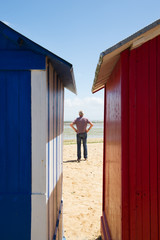 man on the beach in front of beach huts