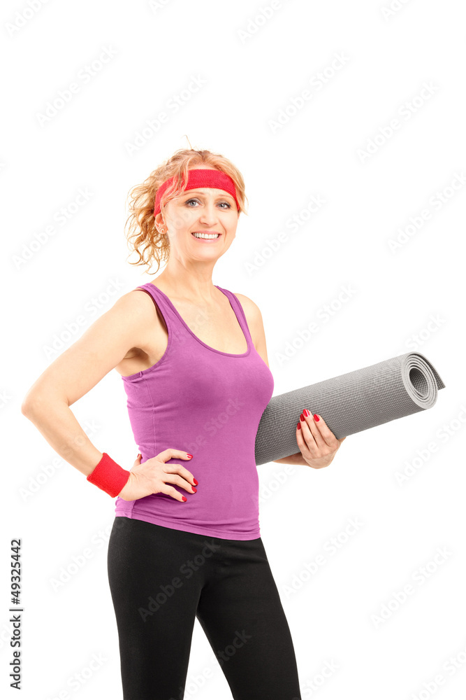 Wall mural A smiling mature female athlete holding a mat