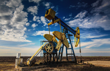 Operating oil well profiled on dramatic cloudy sky