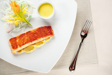 delicious fish, salad lemons and souce on dish with fork
