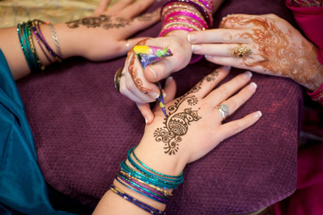 Artist Applying Peacock Henna Design to a Woman's Hands