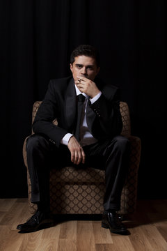 Man with cigarette sitting in vintage armchair