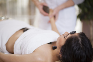 Obraz na płótnie Canvas Pretty young woman getting a stone massage at a spa