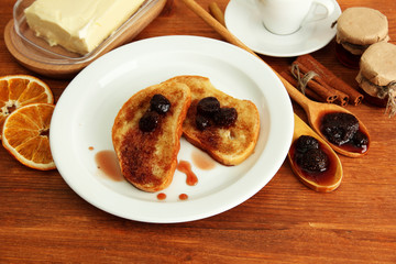 White bread toast with jam and cup of coffee on wooden table