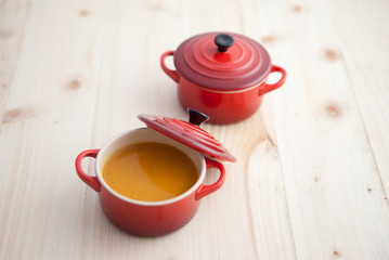 Butternut squash soup in little cocottes on a woden table