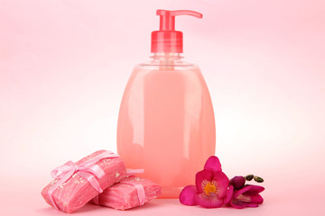 Liquid and hand-made soaps on pink background