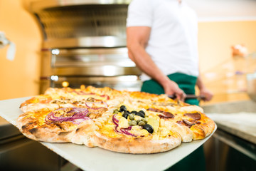 Man pushing the finished pizza from the oven