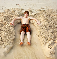 boy  is lying in a sandy bed at the beauti ful beach © travelview