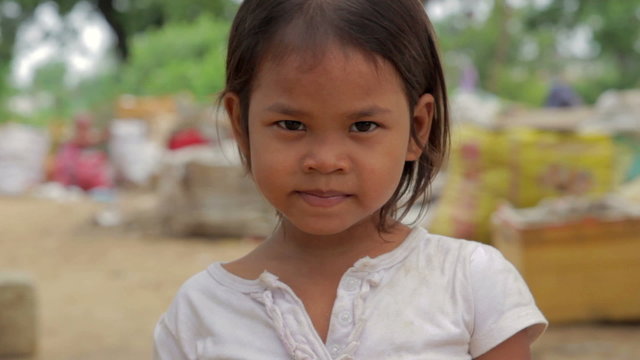 Cambodian girl in slums, garbages at background