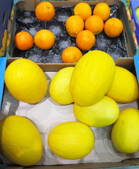 a lot of melon and oranges in market place