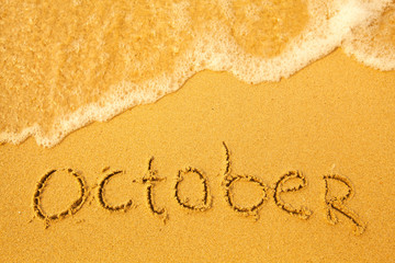 October - written in sand on beach texture