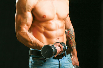 Fototapeta na wymiar Muscular man working out with dumbbells over black background