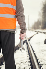 Fototapeta na wymiar Pracownik z regulowaną klucz w ręku na przejazdach kolejowych