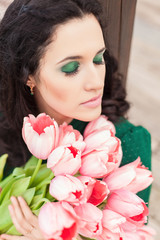 Beautiful young brunette woman with pink tulips