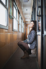 Jeune femme accroupie et adossée dans un train