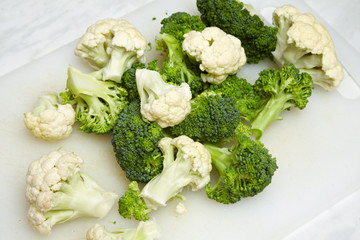 cauliflower and broccoli pieces on white cutting board