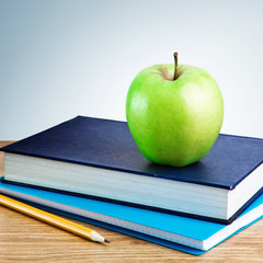 Book, notebook with apples and pencil on table