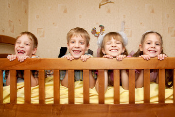 Smiling children, brothers and sisters lying on bed