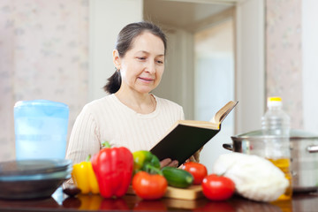  woman cooking with cookbook in kitchen at home