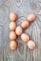 A letter k from the eggs for Easter. On a wooden texture.