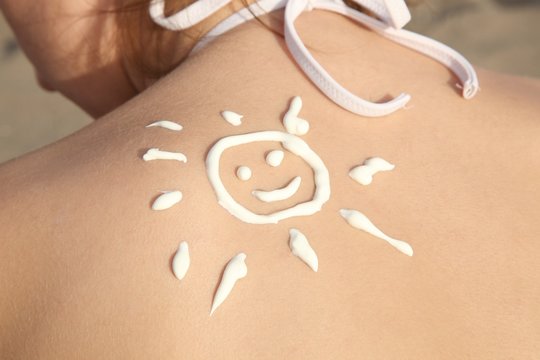 Sonne aus Sonnencreme auf Schulter einer Frau