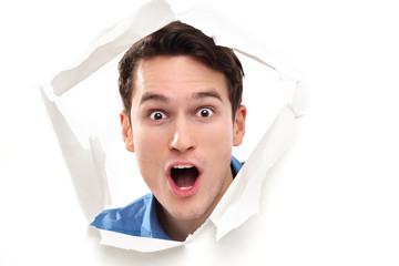 Shocked man looking through paper hole