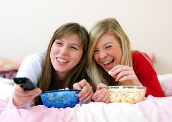 Dos amigas disfrutando y comiendo palomitas de maíz.viendo tv