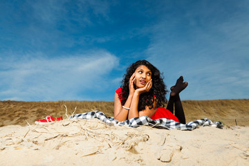 Fototapeta na wymiar Indian girl with long hair dressed in red on the beach in summer