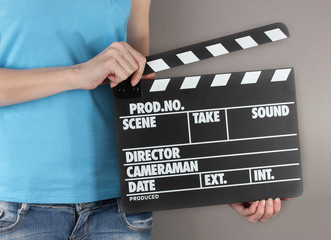 Movie production clapper board in hands on grey background