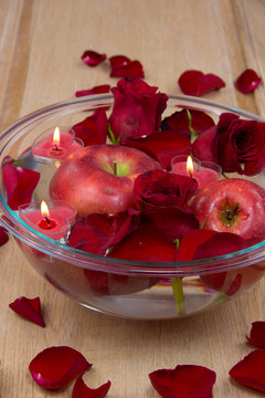 Heart candles in bowl with rose petals and apple