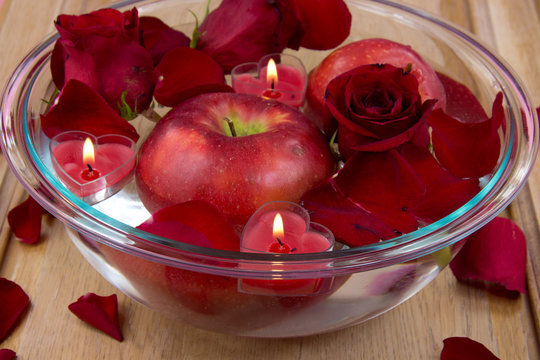 Heart candles in bowl with rose petals and apple