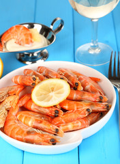 Shrimps with lemon on plate on wooden table close-up