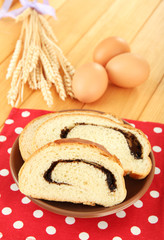 Loaf with poppy seeds on color plate, on wooden background