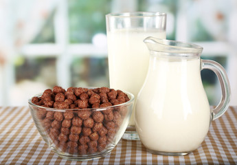 Delicious and healthy cereal in bowl with milk on table in room