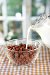 Delicious and healthy cereal in bowl with milk on table in room