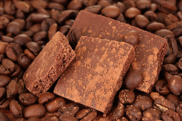 Chopped chocolate with cocoa, on coffee beans background