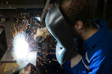 Man welding steel creating many sparks - obrazy, fototapety, plakaty