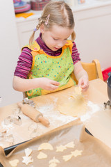 Little girl is baking some cookies in the kitchen