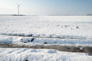 Wind turbine in a snowy field in sunlight