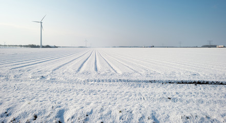 Wind turbine in a snowy field in sunlight
