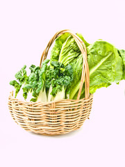 Naklejka premium Fresh baby bok choy and cos salad in ratten basket isolated on