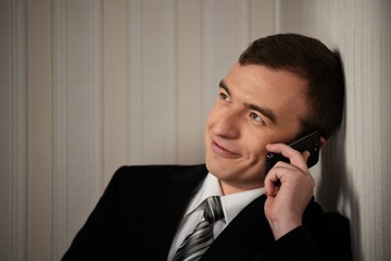 Handsome man in black suit with cell phone talking