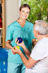Physiotherapeutin zeigt Übung mit Igelball